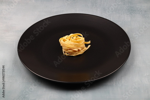 Uncooked tagliatelle in a black plate