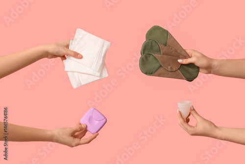 Female hands with menstrual cup, tampons storage box and reusable pads on pink background