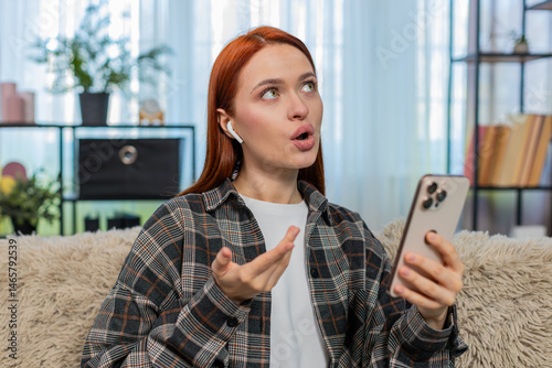Obraz na plátně Young woman at home learning new language using mobile app and repeating words aloud with focus and joy