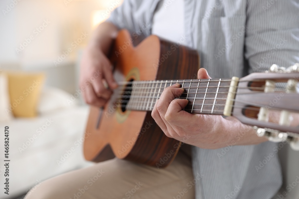 Fototapeta premium Man playing guitar at home, focus on hand
