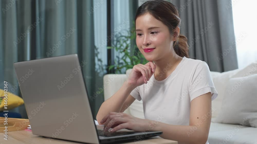 beautiful asian young woman wear casual sit on couch using computer laptop entertain with social media relax smile and laughing.Freelance woman working online sale marketing. Shopping online at home beautiful asian young woman wear casual sit on couch using computer laptop entertain with social media relax smile and laughing.Freelance woman working online sale marketing. Shopping online at home