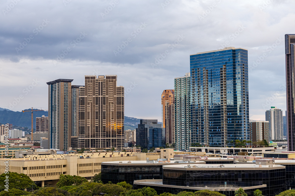 Obraz premium Modern Skyscrapers in Honolulu Against a Cloudy Hawaiian Skyline