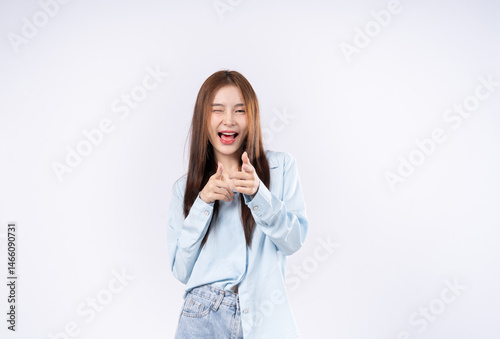 Smiling happy woman pointing at the camera with both hands  with a playful expression and focus to her face on white background