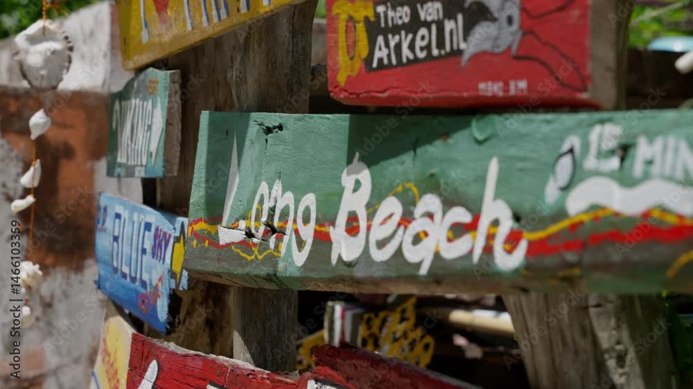 Weathered wooden direction signs pointing toward long beach and local town, revealing tropical thai landscape with vibrant colors blending together