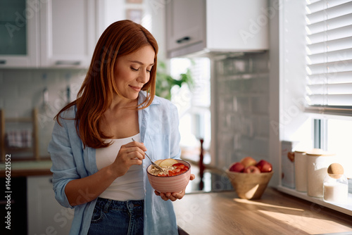Foto Smiling woman having healthy breakfast in kitchen.