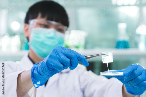 Scientist conducts an experiment using biotechnology to test an organic aloe vera beauty serum under a microscope for a new cosmetic product, Laboratory and skincare concept