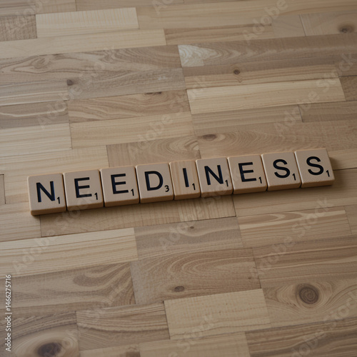 The concept of Neediness represented by wooden letter tiles