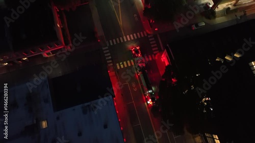 Blinking red lights of fire truck on street in american town at night. Aerial top down shot. Junction of downtown in USA.