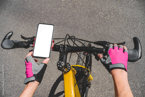 Close-up mockup of a white mobile phone screen on a bicycle handlebar. Background of gray asphalt or concrete on the road outdoors.