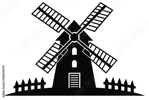 Black rural windmill with wooden fence and arched windows stands silently in silhouette