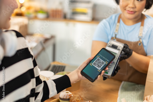 Small business owners are selling .Handsome young caucasian waiter servicing the customer with swiping machine in a cafe. Cashless contactless payment with credit debit card. E-banking .