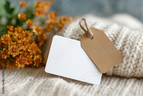 Warm and cozy label mockup with kraft paper tag on knitted fabric, styled with fresh flowers – perfect for handmade product branding, craft packaging, or natural lifestyle designs.