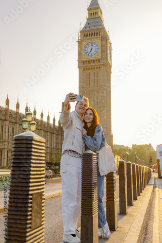 A joyful couple takes a playful selfie in front of Big Ben, capturing the essence of their London visit. The warm sunlight enhances the romantic atmosphere of their cherished moment