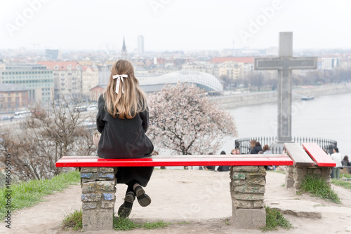 Young woman sitting alone on a bench against city view