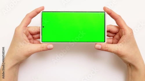 Woman,s hands holding smartphone with green screen on white background