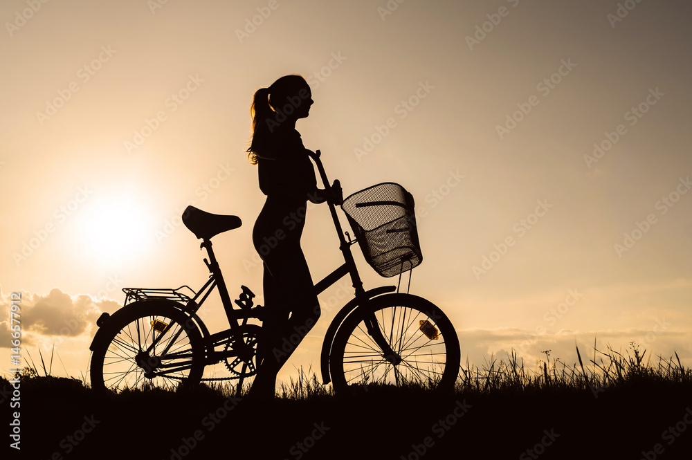 Obraz premium Silhouette of a woman with a bicycle. Sunset background.