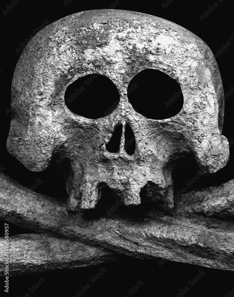 An ancient stone statuue of human skull as symbol of death and horror on bkack background. Vertical image.