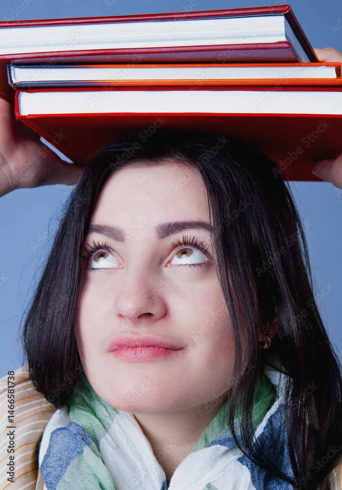 Portrait of female student balancing books on her head as symbol of education, knowledge and self development. Vertical image.