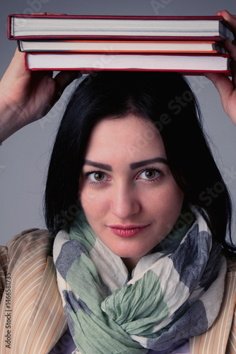 Obraz na płótnie Young Student Girl Balancing Books on her Head. Vertical image. w salonie
