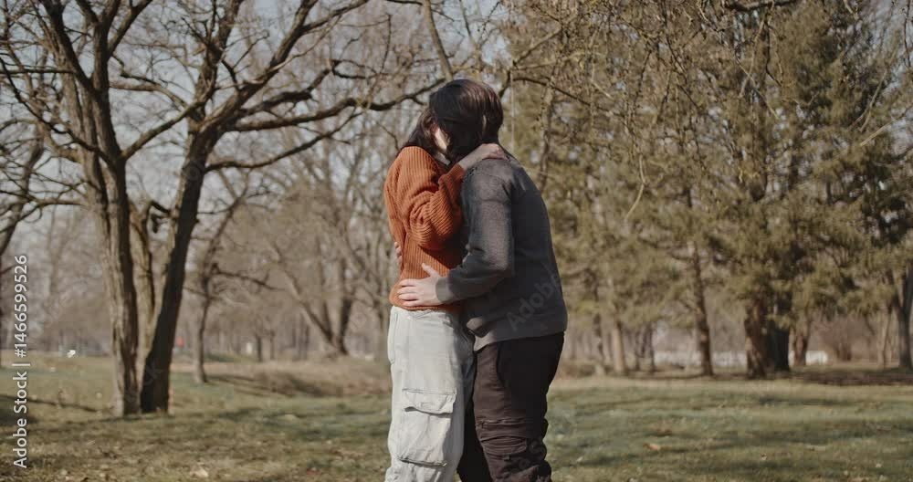 Young couple in love enjoying a sunny winter day together in the park. They are kissing and hugging while feeling very happy. Young couple in love enjoying a sunny winter day together in the park. They are kissing and hugging while feeling very happy.