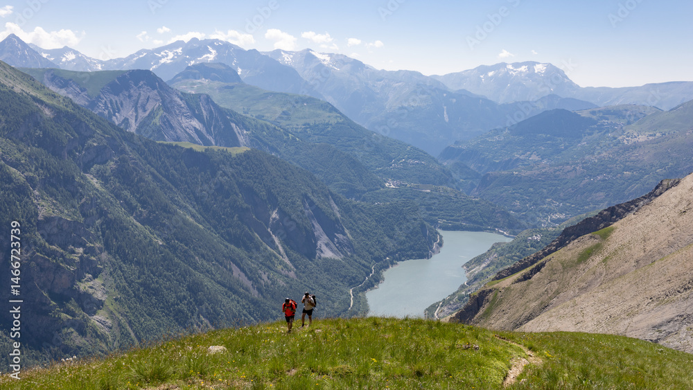 Fototapeta premium randonneur arrivant sur le plateau d'Emparis depuis vallée du Ferrand et le lac de Chambon dans les Alpes de l'Isère en été