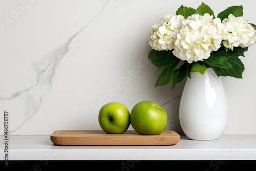 Fresh green apples on a wooden tray beside a white vase filled with hydrangeas, set against a marble wall, creating a serene and elegant kitchen atmosphere. Copy space for text