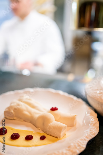 Obraz na płótnie Elegant gourmet dessert on a white plate, shaped like a reclining figure, drizzled with berry sauce and cream. Artful food presentation in a restaurant setting w salonie