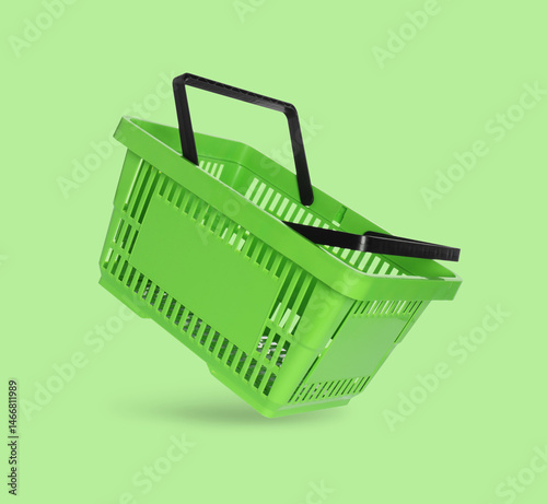 Foto Green shopping basket in air on color background