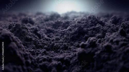Close-up view of textured dark soil or ash with a soft light illuminating the background, creating a moody atmosphere