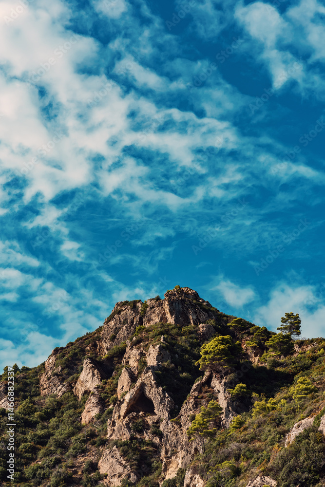 Rocky mountain with green vegetation pine trees under blue sky with fluffy clouds. Rocky mountain with green vegetation pine trees under blue sky with fluffy clouds.