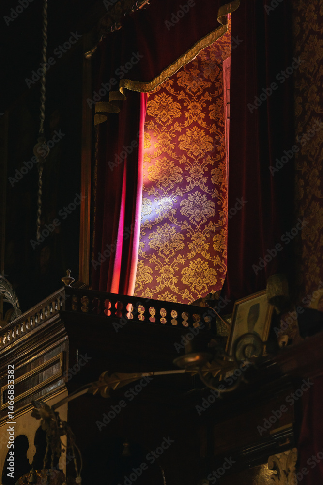 Interior of ancient place of worship with red cloths by a window.