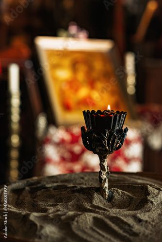 Candlestick with candle on a bowl of sand in an old memorial chapel.