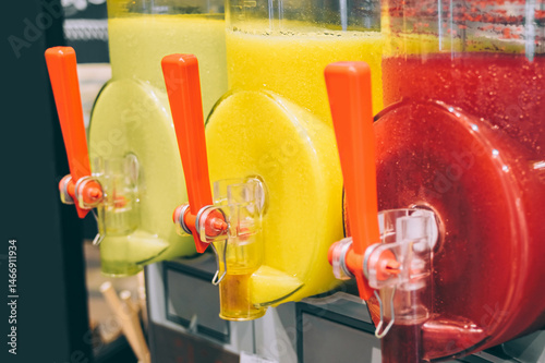 Three slushy machines with vibrant red and yellow frozen drinks.