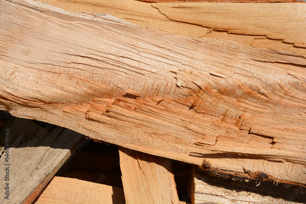 A close-up shows a jumbled stack of light brown firewood pieces with visible wood grain