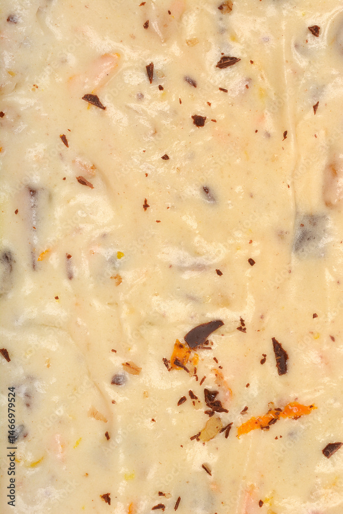 A detailed close-up shows the surface texture of white cake batter with scattered walnuts, dark chocolate pieces, and bright orange zest