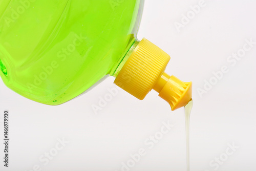 Obraz na płótnie Tilted clear plastic bottle with a yellow cap pours a stream of light green dish soap w salonie