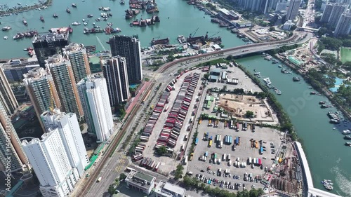Aerial skyview of Tuen Mun subway extension project in Hong Kong, featuring elevated railway construction along Tuen Mun River and road, new station development and temporary work platforms