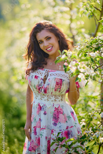 Obraz na płótnie portrait of a beautiful woman in a dress in a blooming apple orchard enjoying a sunny spring day w salonie