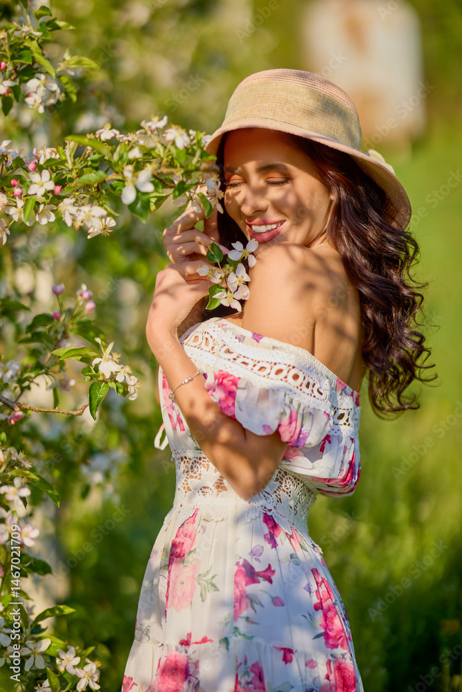 portrait of a beautiful woman in a dress in a blooming apple orchard enjoying a sunny spring day
