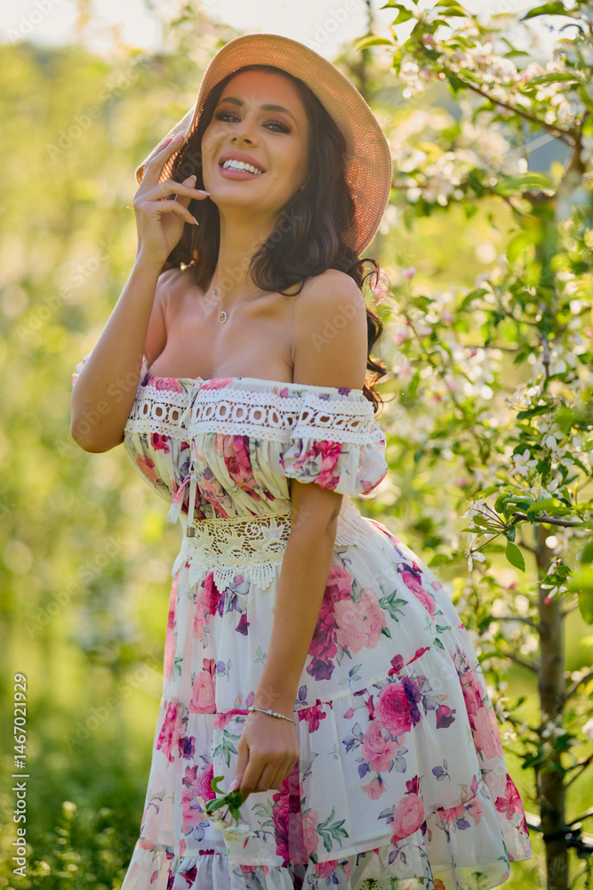 portrait of a beautiful woman in a dress in a blooming apple orchard enjoying a sunny spring day