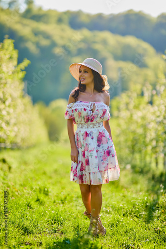 Obraz na płótnie Full body portrait of a beautiful woman in a dress in a blooming apple orchard on a sunny spring day w salonie