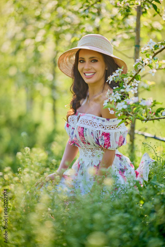 portrait of a beautiful woman in a dress in a blooming apple orchard enjoying a sunny spring day