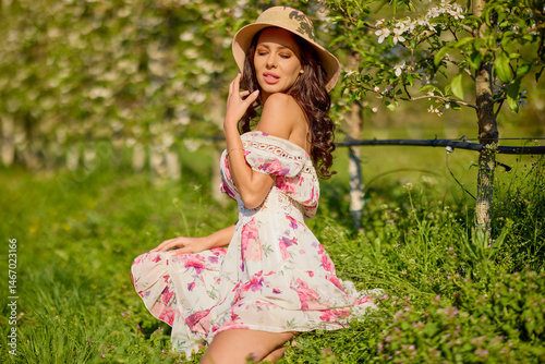 portrait of a beautiful woman in a dress in a blooming apple orchard enjoying a sunny spring day