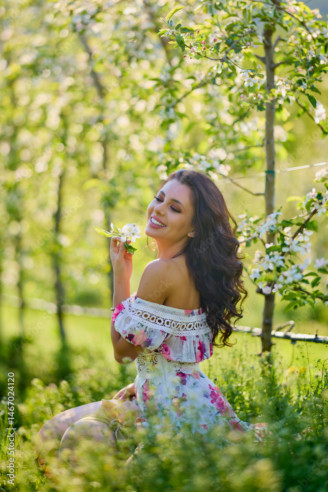 portrait of a beautiful woman in a dress in a blooming apple orchard enjoying a sunny spring day