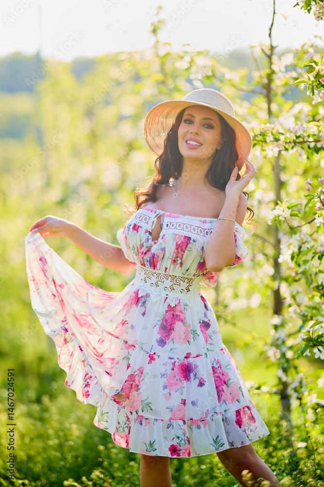 portrait of a beautiful woman in a dress in a blooming apple orchard enjoying a sunny spring day