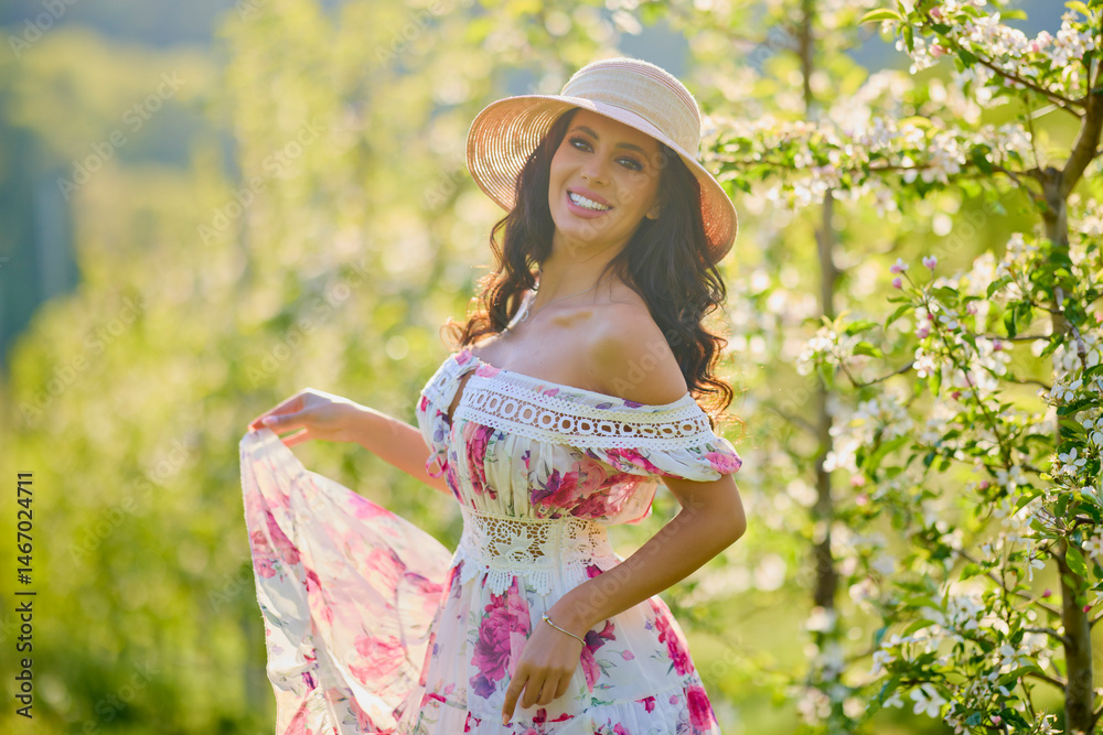 portrait of a beautiful woman in a dress in a blooming apple orchard enjoying a sunny spring day