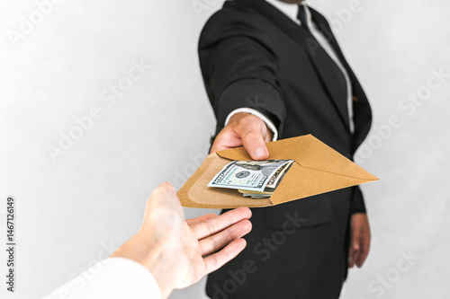 Businessman Handing Envelope Full of US Dollars to Another Person.