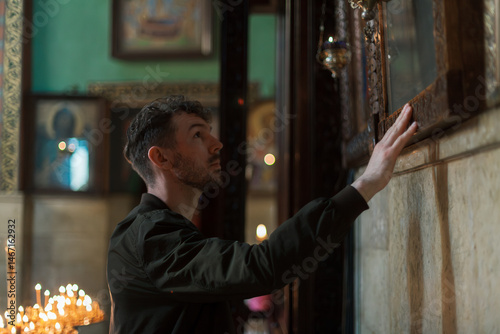 Modern Orthodox Christian man praying and lighting candles in a monumental Georgian church. A personal spiritual connection and moment of faith