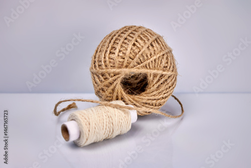 close-up image of a ball and spool of threads made of natural hemp fibers on a gray background, creative focus, the concept of organic eco-friendly fibers