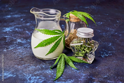 a jug of hemp milk, a jar of hemp seeds, a star-shaped jar with dried hemp inside, hemp leaves and twigs on a dark blue background, the concept of a healthy, balanced, ecological diet